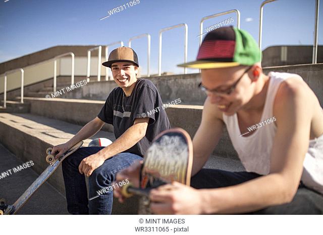 Caucasian men with skateboards sitting on steps