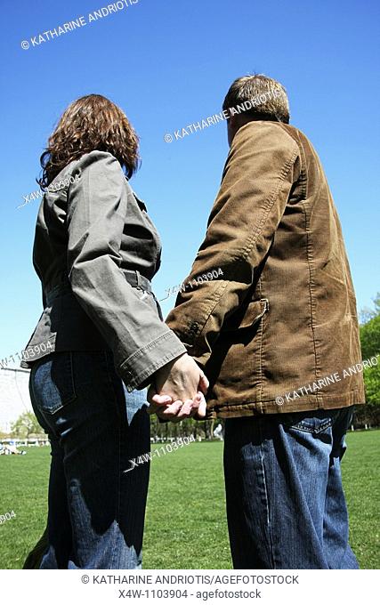 Couple holding hands and looking away on a sunny day in a park