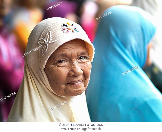 An smiling elderly Muslim woman wearing a embroidered hijab