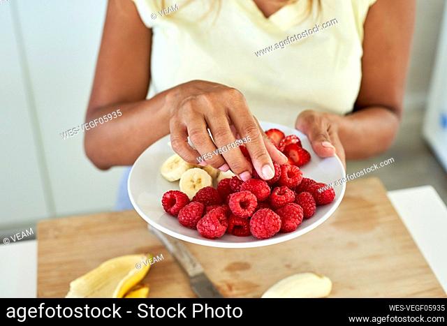 Woman with plate of fruits in kitchen