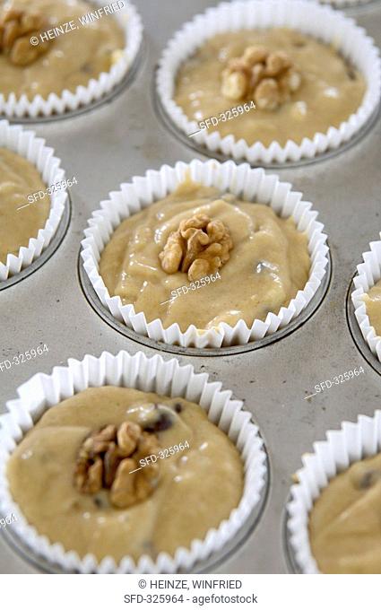 Banana & chocolate muffin mixture with walnuts in muffin tin