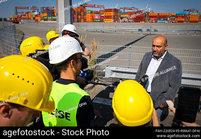 24 August 2022, Hamburg: Omid Nouripour (r), Federal Chairman of Bündnis 90/Die Grünen, gives an interview during his visit to the Container Terminal...