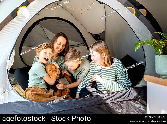 Happy family with Vizsla dog playing in tent at home