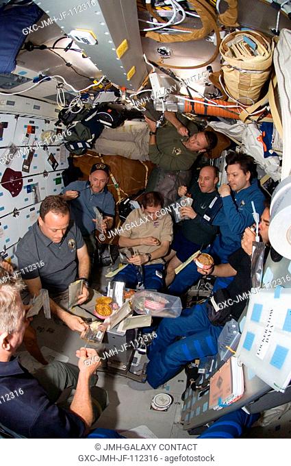 A fish-eye lens on a digital still camera was used to record this image of the STS-124 and Expedition 17 crewmembers as they share a meal on the middeck of the...