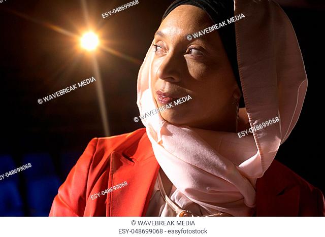 Businesswoman looking and thinking while standing on stage in auditorium