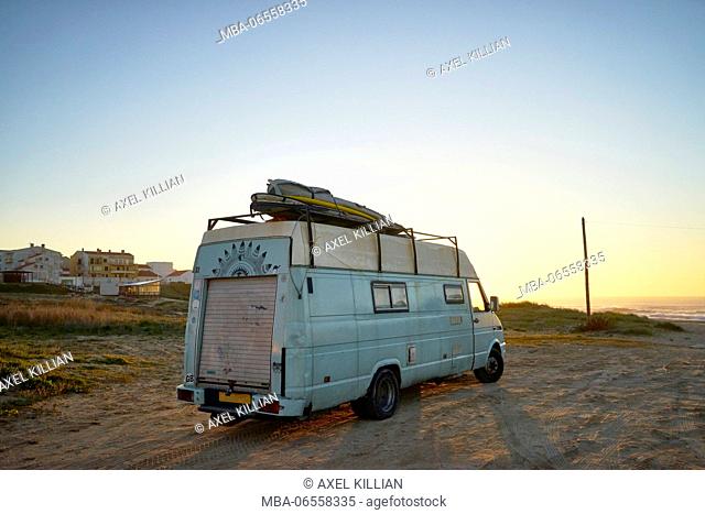 Old camper on the beach, surfboard on the roof