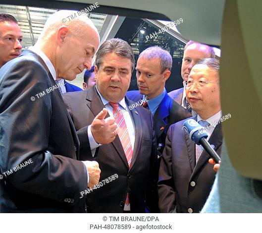 Head of BMW China, Karsten Engel (L) shows German Minister for Economic Affairs and Energy Sigmar Gabriel (SPD, C) and Chinese Vice-Minister of Industry and...