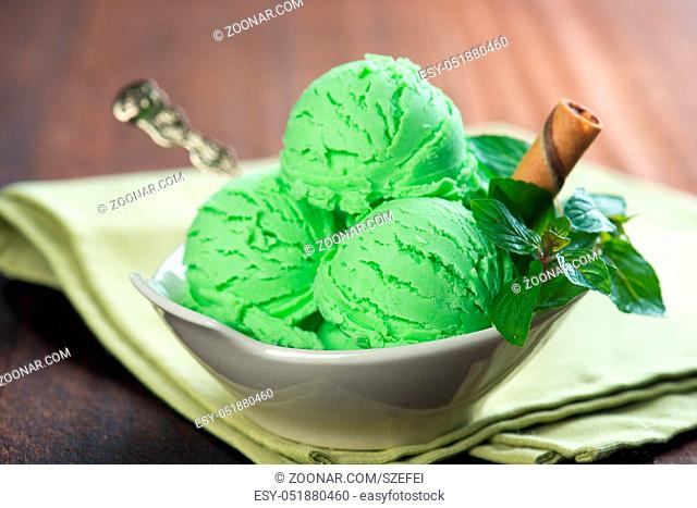 Mint ice cream in bowl on wooden background