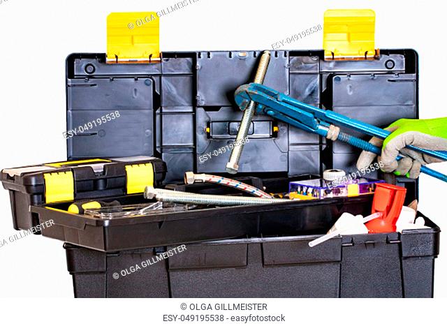 Plumber or carpenter tool box isolated. Black plastic tool kit box with assorted tools and a hand with glove holding a big screw with a big pipe wrench