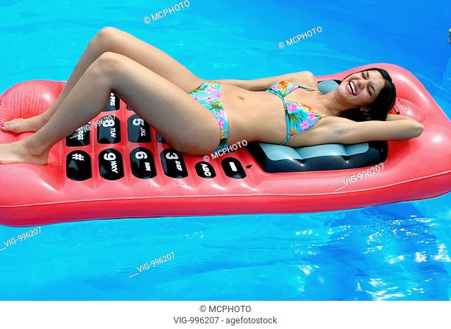 Woman on a mobile phone shaped air bed in a pool - 12/09/2008
