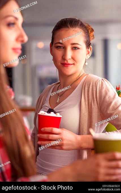 Toned picture of pretty lady drinking delicious coffee while sitting in cafe or restaurant. Woman looking at camera and spending free time with friends