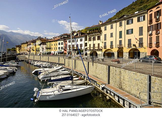 DOMASO, ITALY - OCTOBER 04: fall sun lightens harbor, old houses and little traffic on ancient ""Regina"" road crossing historical touristic village on Lario...