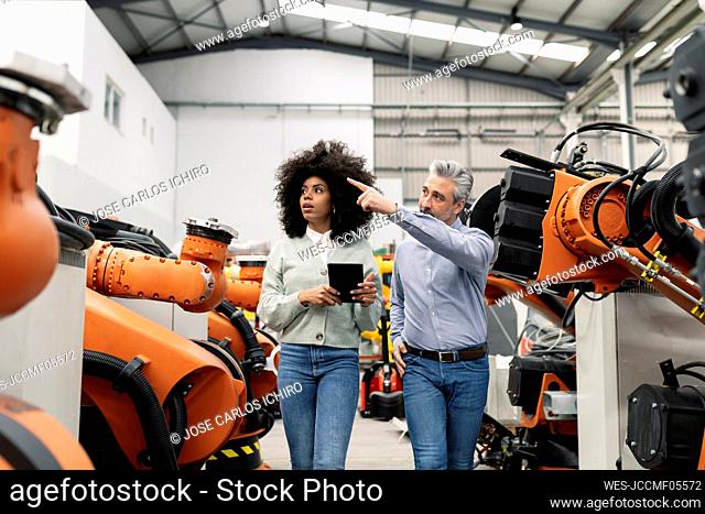 Engineer showing machine to technician in factory