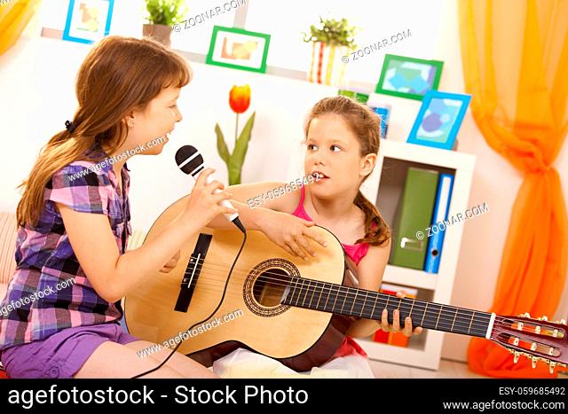 Elementary age girls playing music and singing together at home, having fun