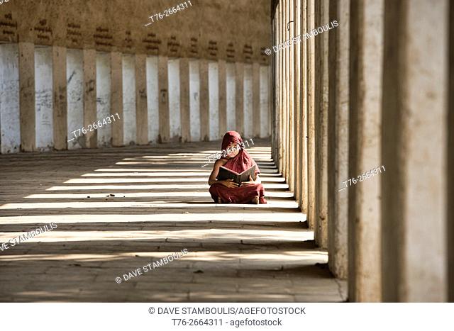 A young monk reading in the entrance to Shwezagon Pagoda, in Bagan, Myanmar