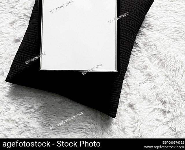 Thin wooden frame with blank copyspace as poster photo print mockup, black cushion pillow and fluffy white blanket, flat lay background and art product