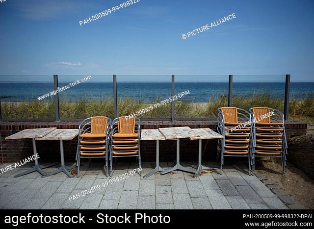 09 May 2020, Schleswig-Holstein, Timmendorfer Strand: Tables and chairs are tied together on the terrace with sea view of a restaurant on the beach promenade in...