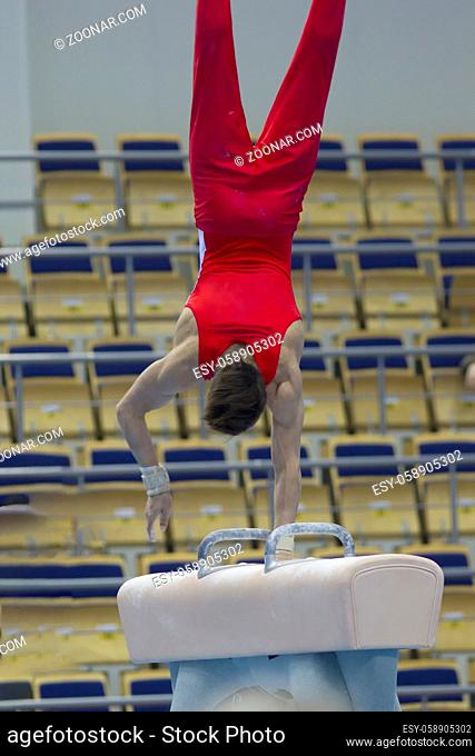 Young athletic man performing on pommel horse, close up