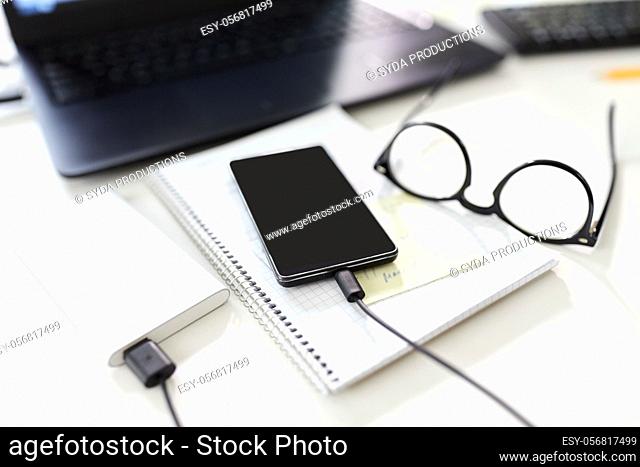 smartphone with power bank on table at office