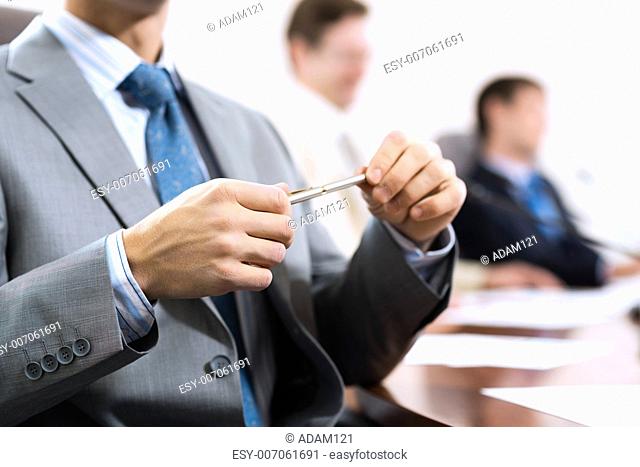 businessman sitting at a table and holding a pen