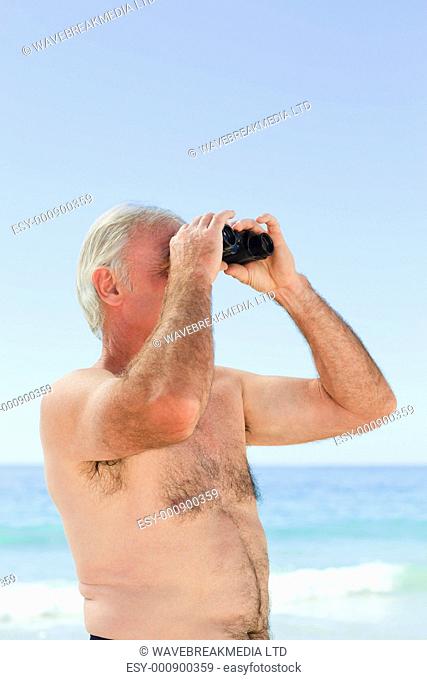 Senior man bird watching at the beach