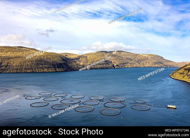 Salmon fish farm in ocean water near mountain at the coast of Streymy Island, Faroe Islands