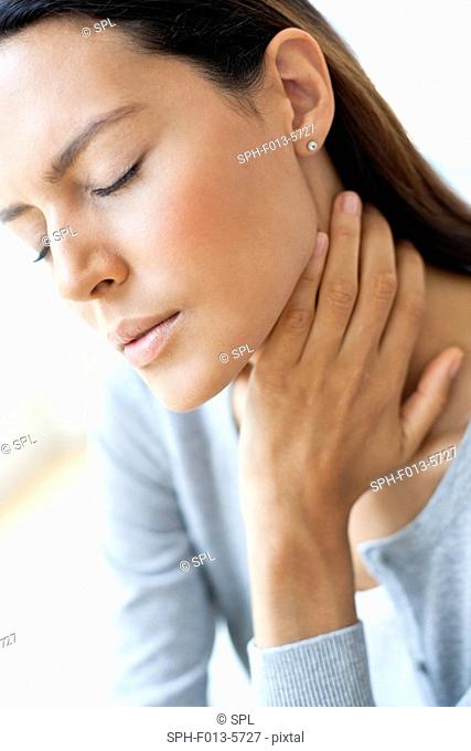 MODEL RELEASED. Young woman touching her neck in pain