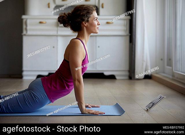 Woman using digital tablet while doing yoga at home