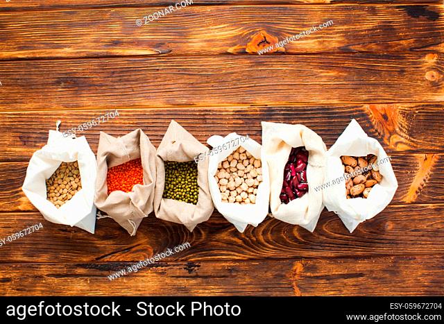 Textile bags with natural cereal food on wooden table, copy space, top view