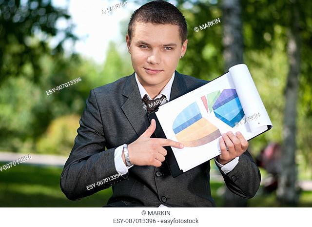 Young business man show graph on outdoor meeting, at green park. Student