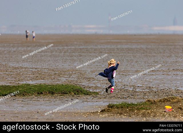 Harlesiel / Carolinensiel, Germany June 2020: Symbolic pictures - 2020 A little girl runs through the Wadden Sea in front of Harlesiel at low tide