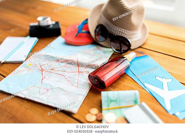 summer vacation, tourism and objects concept - close up of travel map, airplane tickets, money and personal accessories