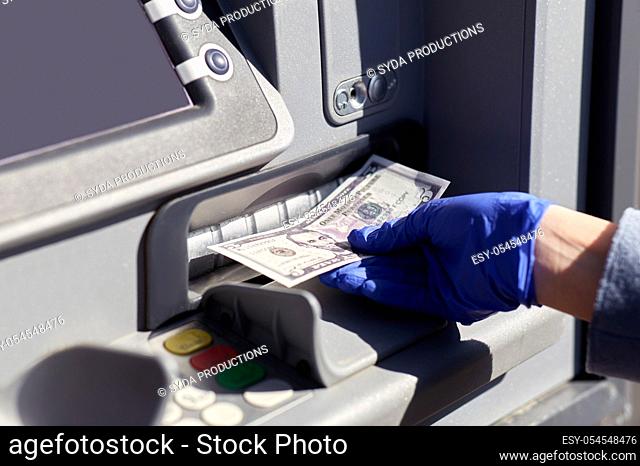 hand in medical glove with money at atm machine