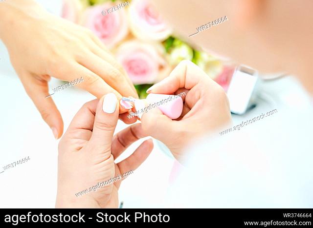 Experienced nail technician applying nail color to fingernails