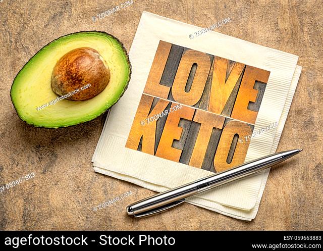 love keto, high fat ketogenic diet concept - word abstract in vintage letterpress wood type on a napkin with a cut avocado