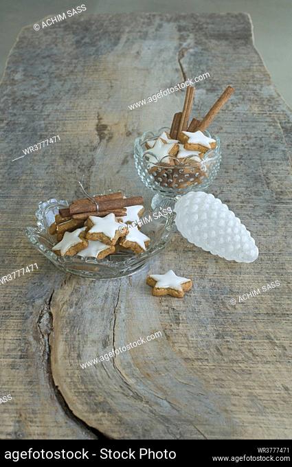 Star-shaped cinnamon biscuits and cinnamon sticks in glass bowls