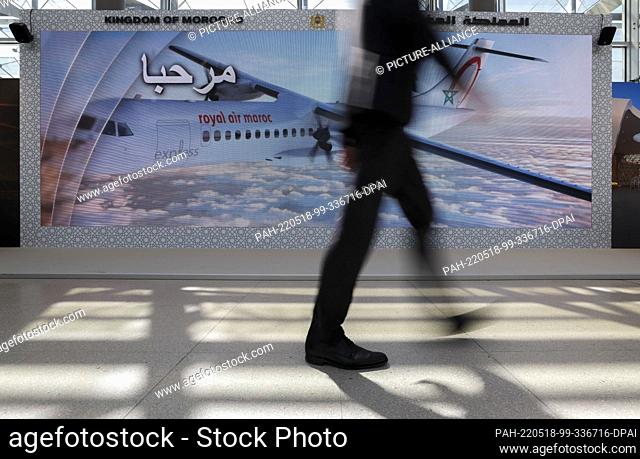 18 May 2022, Saxony, Leipzig: A visitor to the International Transport Forum walks through the Congress Center Leipzig on a video screen of Morocco