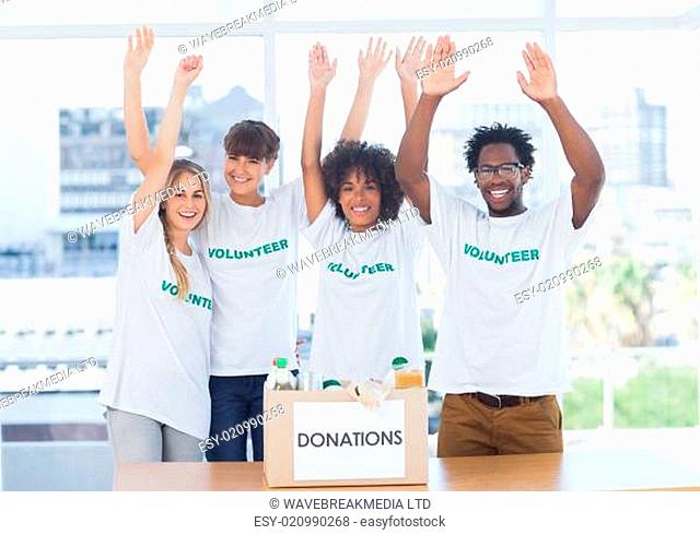 Volunteers raising their arms in front of food in a donation box