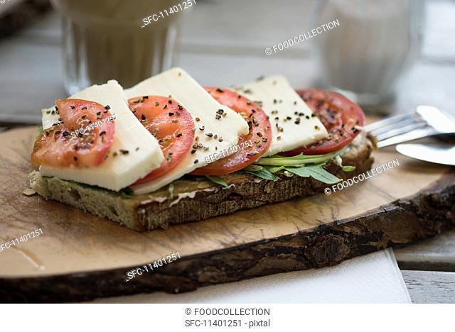 Olive bread topped with tomatoes, mozzarella, rocket and black pepper