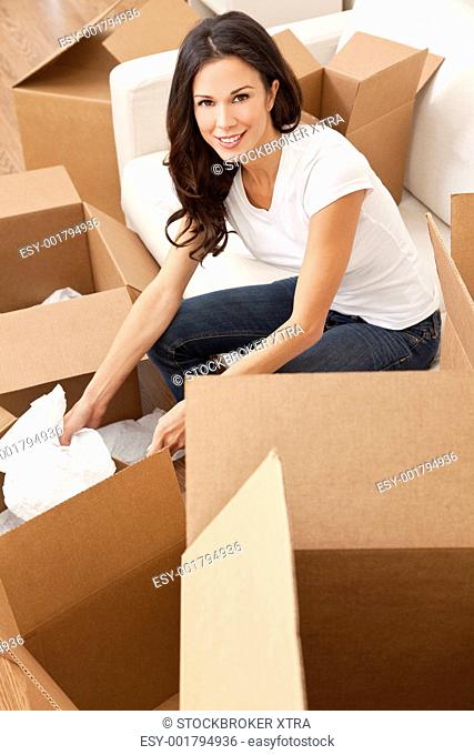 A beautiful single young woman unpacking boxes and moving into a new home