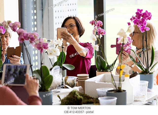 Active seniors with camera phones enjoying flower arranging class