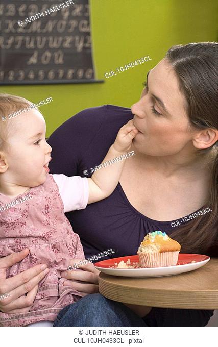 Young girl feeding her mother with cake