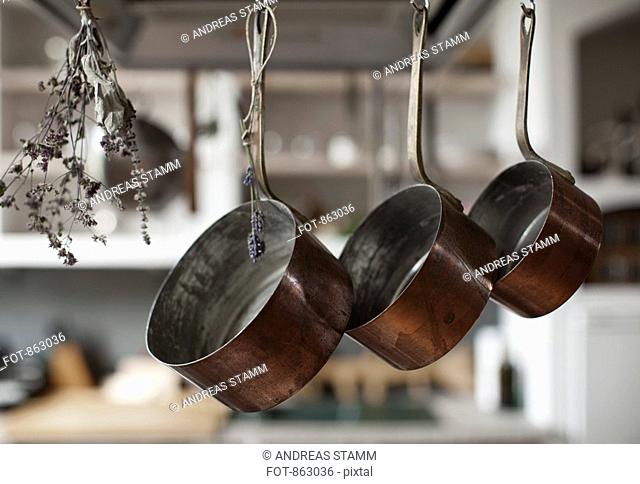 Three saucepans hanging from hooks with dried lavender