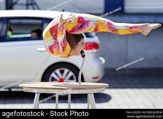 31 May 2020, Baden-Wuerttemberg, Mannheim: A circus artist shows tricks at a circus drive-in of the children and youth circus ""Paletti""