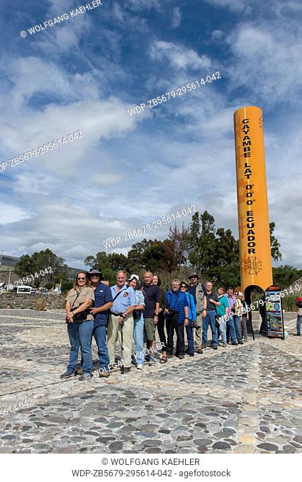 A tour group is standing with one foot in the northern hemisphere and the other foot in the southern hemisphere at the Quitsato equator monument and sundial...