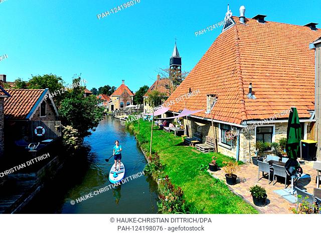 A woman with a stand-up paddling board on a small canal in Hindeloopen (Netherlands), 26 August 2019. | usage worldwide. - Hindeloopen/Friesland/Netherlands