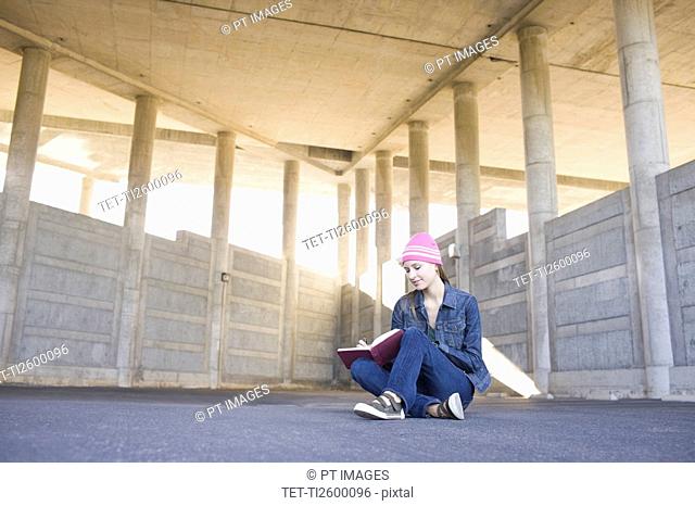 Young woman reading in urban setting