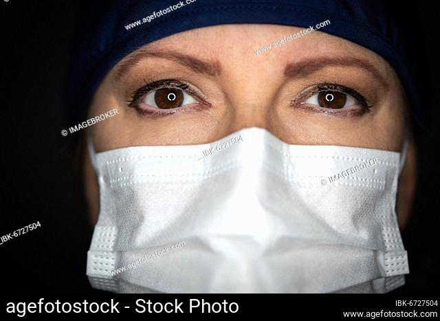 Female doctor or nurse wearing medical face mask on dark background