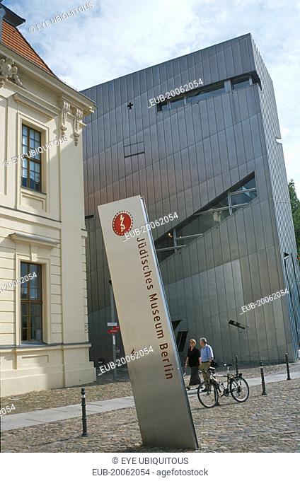 Visitors walking past entrance to the Jewish Museum designed by Polish architect Daniel Libeskind in 1998 with name sign in foreground