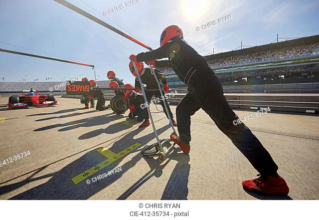 Pit crew preparing for formula one race car pit stop in pit lane